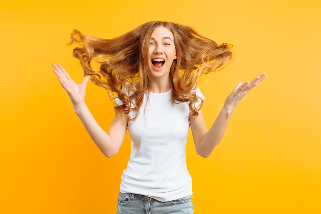 Young Shocked Girl Shocked by Good News, Screaming with Happiness over Yellow Background
